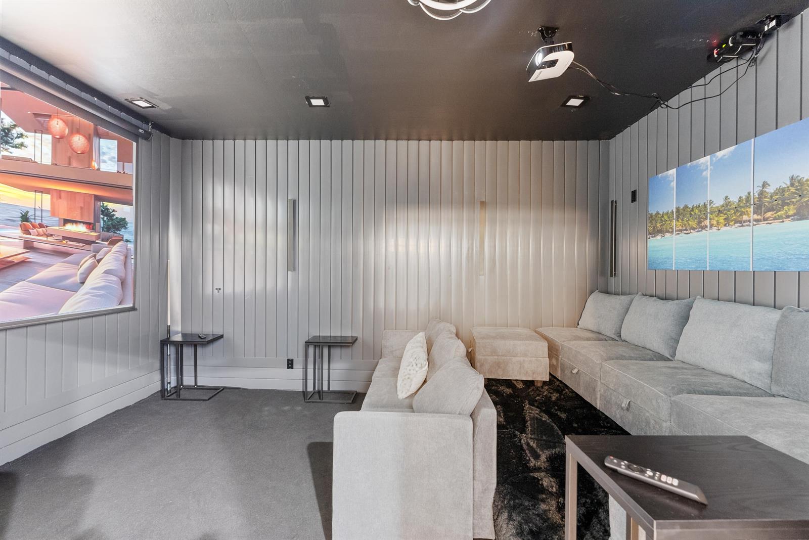 A home theater room features a projector screen, gray paneled walls, and light-colored sectional seating — 11910 Osprey Point Circle, Wellington FL 33449, WELLINGTON, FL