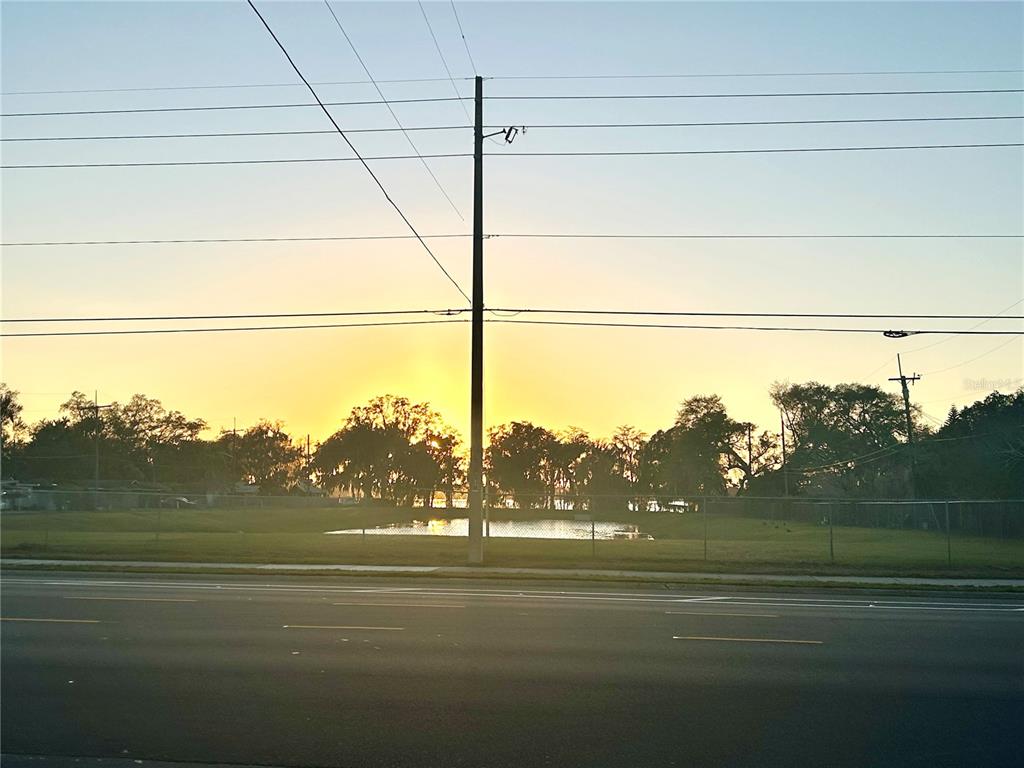 A utility pole stands in front of a small pond and trees at sunset — 2035 S RIO GRANDE AVENUE, ORLANDO, FL
