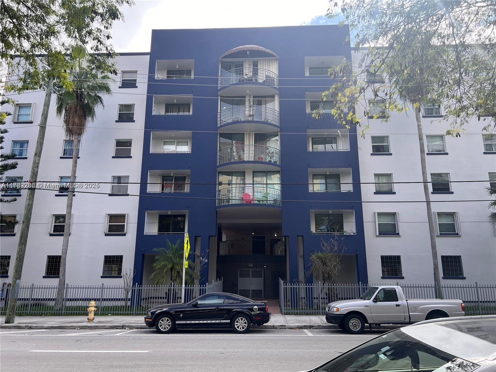 A tiled living area leads to a balcony, with a small kitchen counter in the foreground — 546 SW 1st St # 611, Miami FL 33130, MIAMI, FL