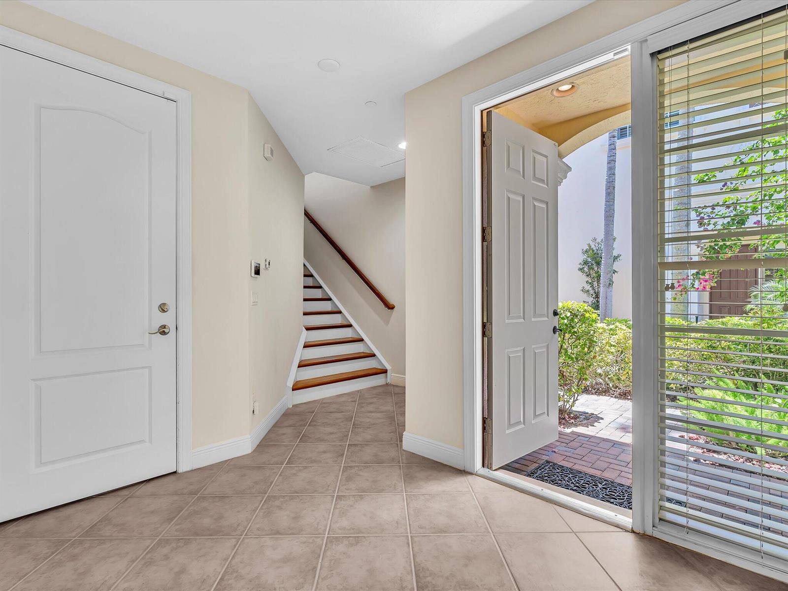 A tiled entryway features a staircase, a closed white door, and an open front door — 5575 NE Trieste Way, Boca Raton FL 33487, BOCA RATON, FL