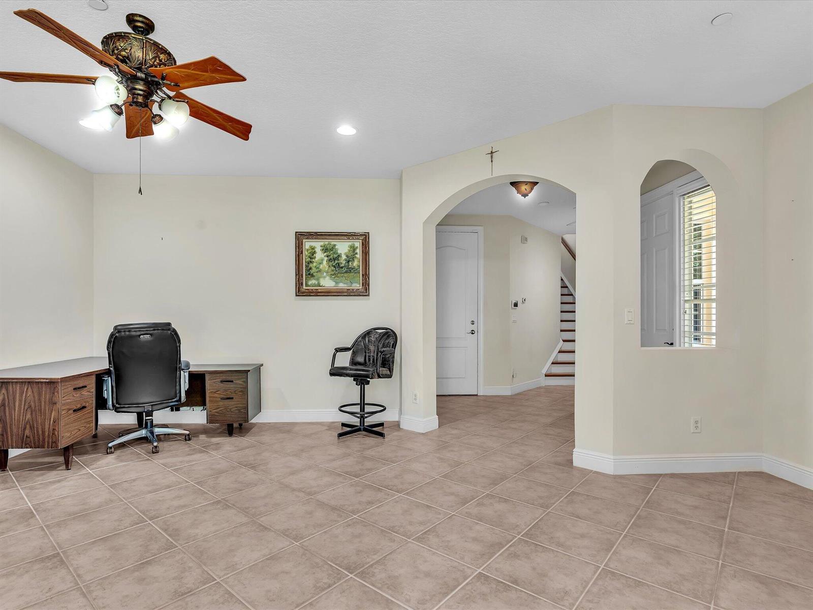 A home office features tile flooring, a desk with a chair, and an arched entryway — 5575 NE Trieste Way, Boca Raton FL 33487, BOCA RATON, FL