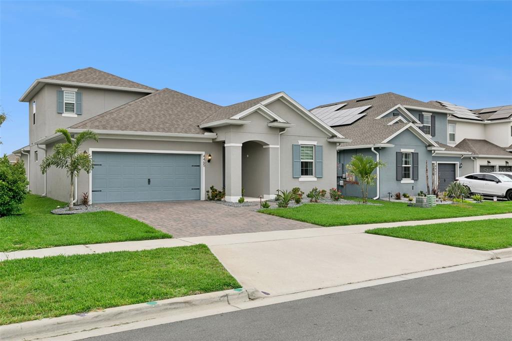 A gray single-story house with a two-car garage, paved driveway, and green lawn — 4465 DAVOS DRIVE, CLERMONT, FL