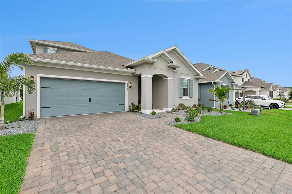 A single-story house with a gray garage door, paved driveway, and a small front yard — 4465 DAVOS DRIVE, CLERMONT, FL