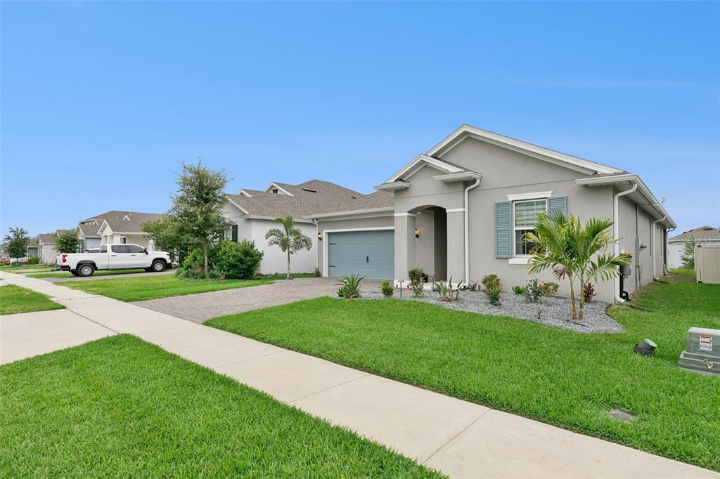 A single-story gray house with a paved driveway, a two-car garage, and a front lawn — 4465 DAVOS DRIVE, CLERMONT, FL