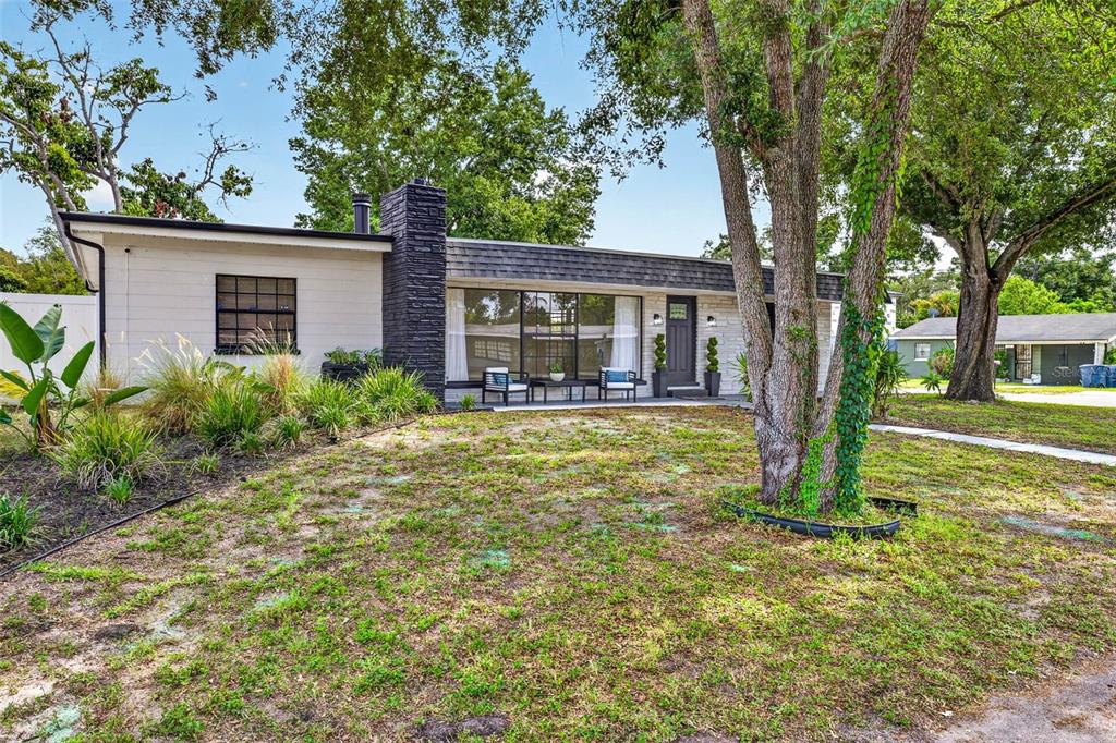 A single-story house with a dark stone chimney, white siding, and a large front window — 1601 E PARIS STREET, TAMPA, FL