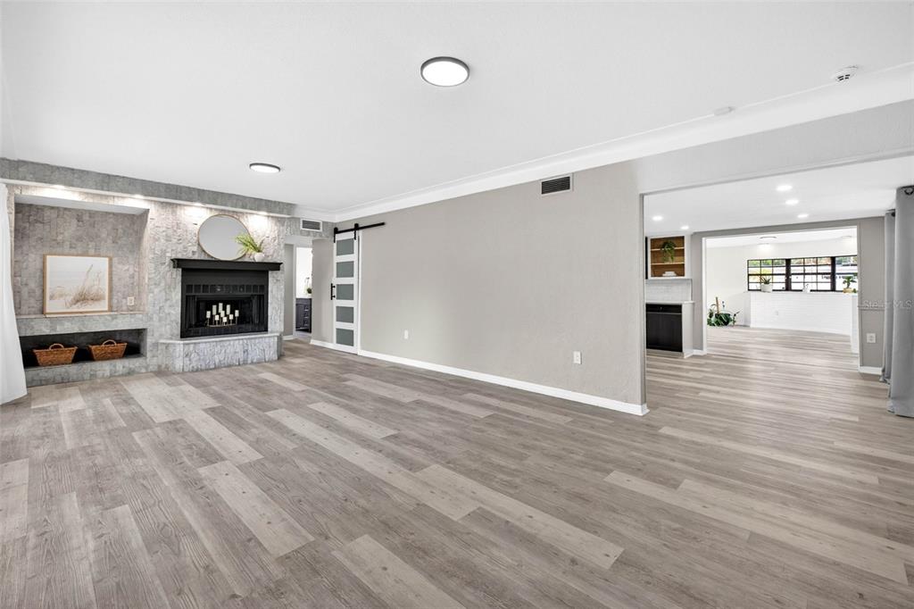 A living room features light wood-look flooring, a stone fireplace, and a sliding barn door — 1601 E PARIS STREET, TAMPA, FL