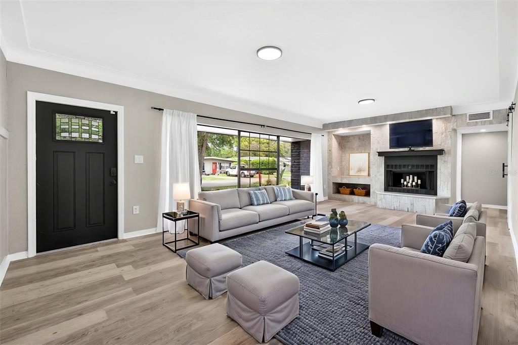 A living room features light wood flooring, a grey sofa, a fireplace, and a black door — 1601 E PARIS STREET, TAMPA, FL