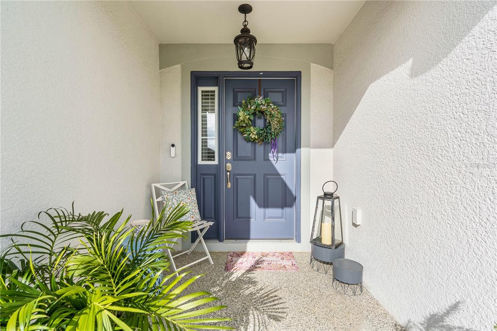 A blue front door with a wreath is centered in a covered entryway with stucco walls — 956 ARUBA AVENUE, MULBERRY, FL