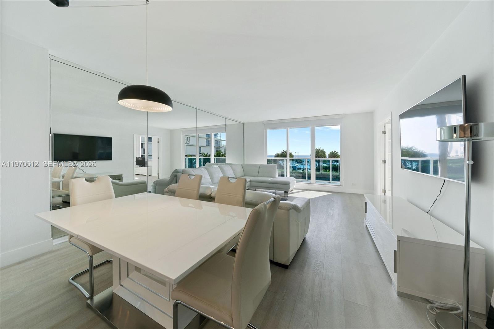 A room with light wood flooring features a white decorative tree, a metal floor lamp, and French doors opening to a bedroom — 2301 Collins Ave # 338, Miami Beach FL 33139, MIAMI BEACH, FL