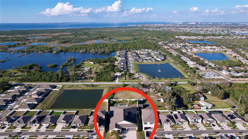 An aerial view shows a residential house circled in red within a suburban neighborhood — 197 RAIN BERRY AVENUE, RUSKIN, FL