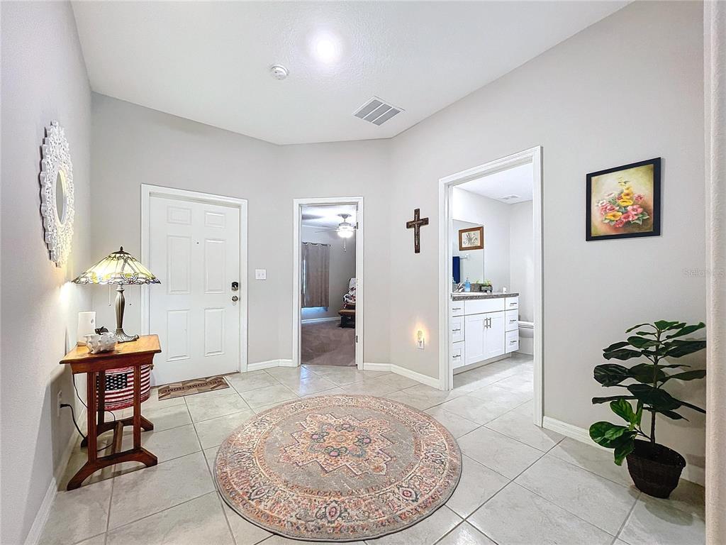 A tiled entryway features a round rug, a side table with a lamp, and two doorways — 197 RAIN BERRY AVENUE, RUSKIN, FL