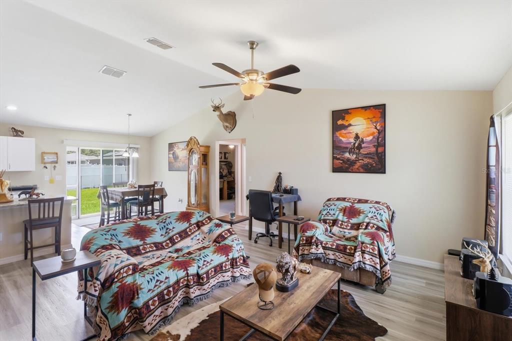 A living room with a vaulted ceiling, ceiling fan, and southwestern-style furniture and decor — 13730 SW 102ND STREET, DUNNELLON, FL