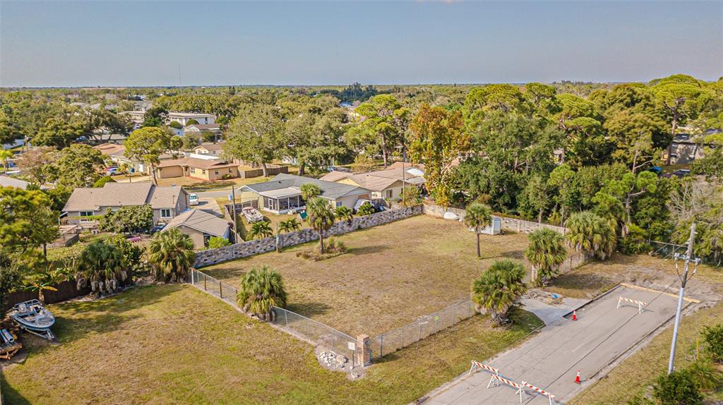 An aerial view shows a vacant, fenced residential lot next to houses and trees — 7598 90TH STREET, SEMINOLE, FL
