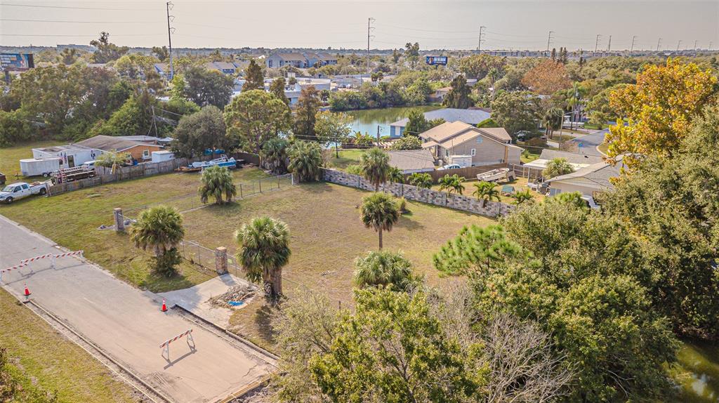 An aerial view shows a vacant, fenced residential lot with several palm trees — 7598 90TH STREET, SEMINOLE, FL