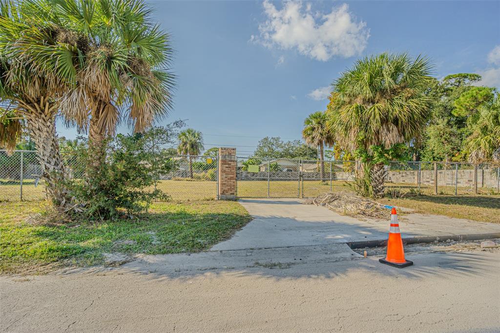 A fenced vacant lot features a concrete driveway, a brick pillar, and several palm trees — 7598 90TH STREET, SEMINOLE, FL