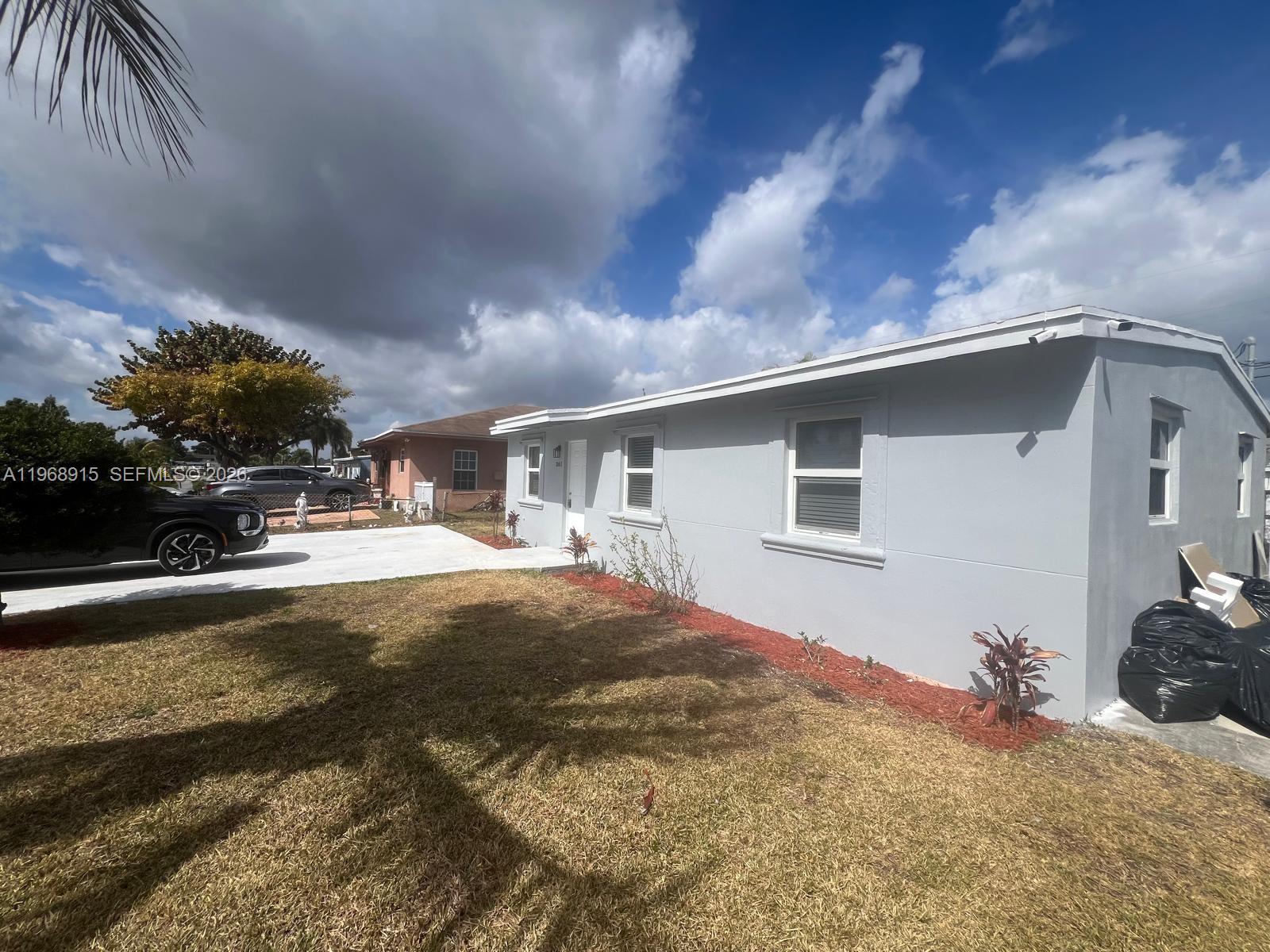 A light gray single-story house features a concrete driveway and a small front yard — 361 NW 16th St, Pompano Beach FL 33060, POMPANO BEACH, FL