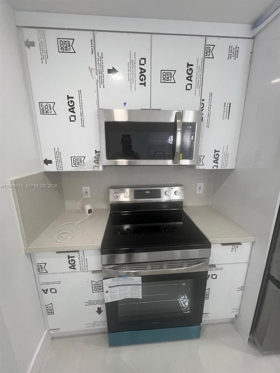 A kitchen features a stainless steel range and microwave surrounded by unfinished white cabinetry — 361 NW 16th St, Pompano Beach FL 33060, POMPANO BEACH, FL