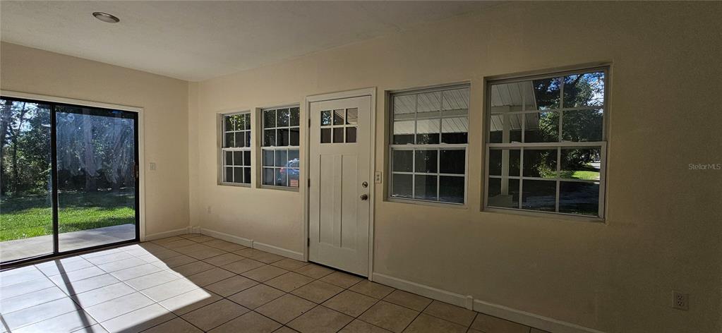 A sunroom features tile flooring, a sliding glass door, and a white exterior door — 709 S HIGHLAND STREET, MOUNT DORA, FL