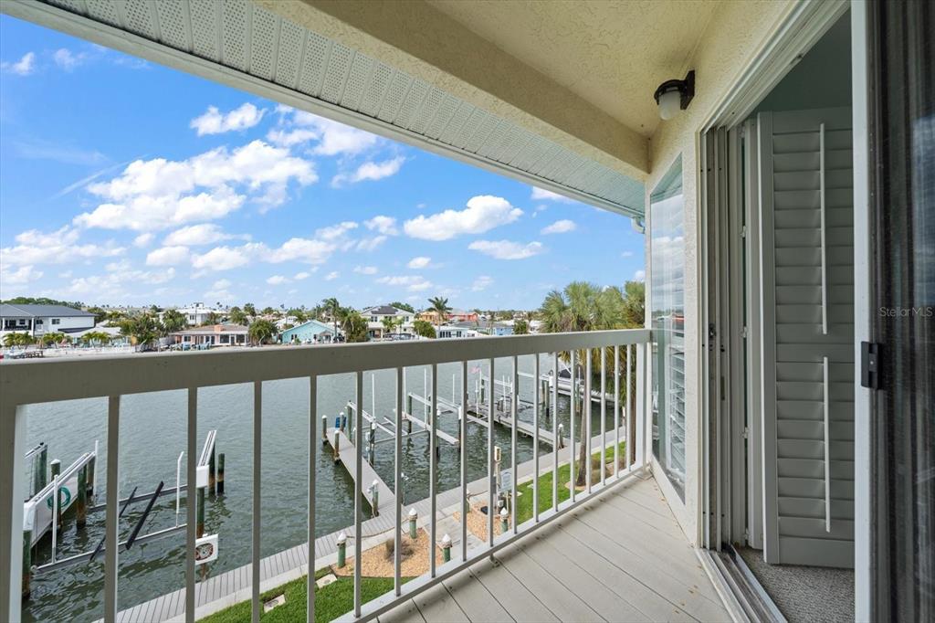 A balcony with a white railing overlooks a canal with boat docks and houses — 124 MARCDALE BOULEVARD, INDIAN ROCKS BEACH, FL