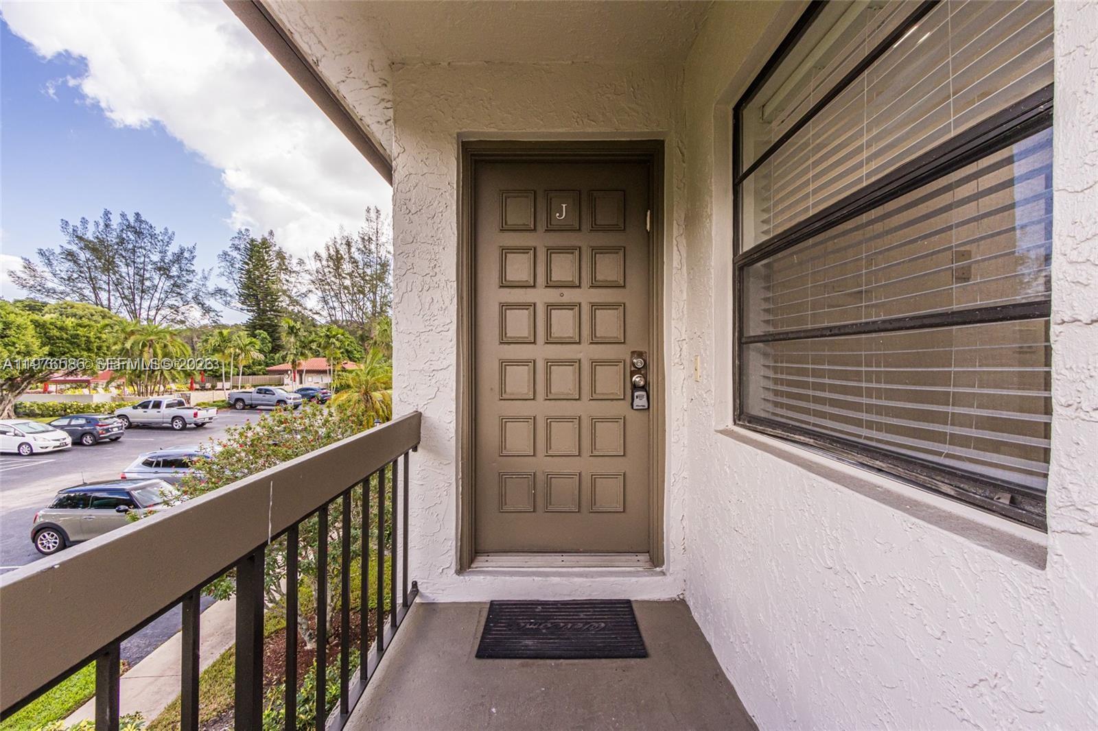 An exterior view shows a brown front door labeled J on a covered balcony — 21529 Cypress Hammock Dr # 35J, Boca Raton FL 33428, BOCA RATON, FL
