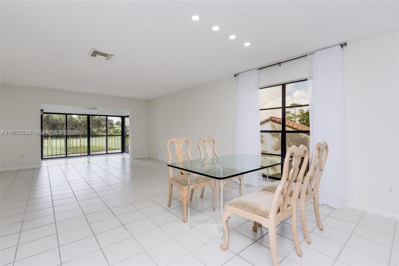 A dining area with a glass table, four chairs, white tile floors, and large windows — 21529 Cypress Hammock Dr # 35J, Boca Raton FL 33428, BOCA RATON, FL