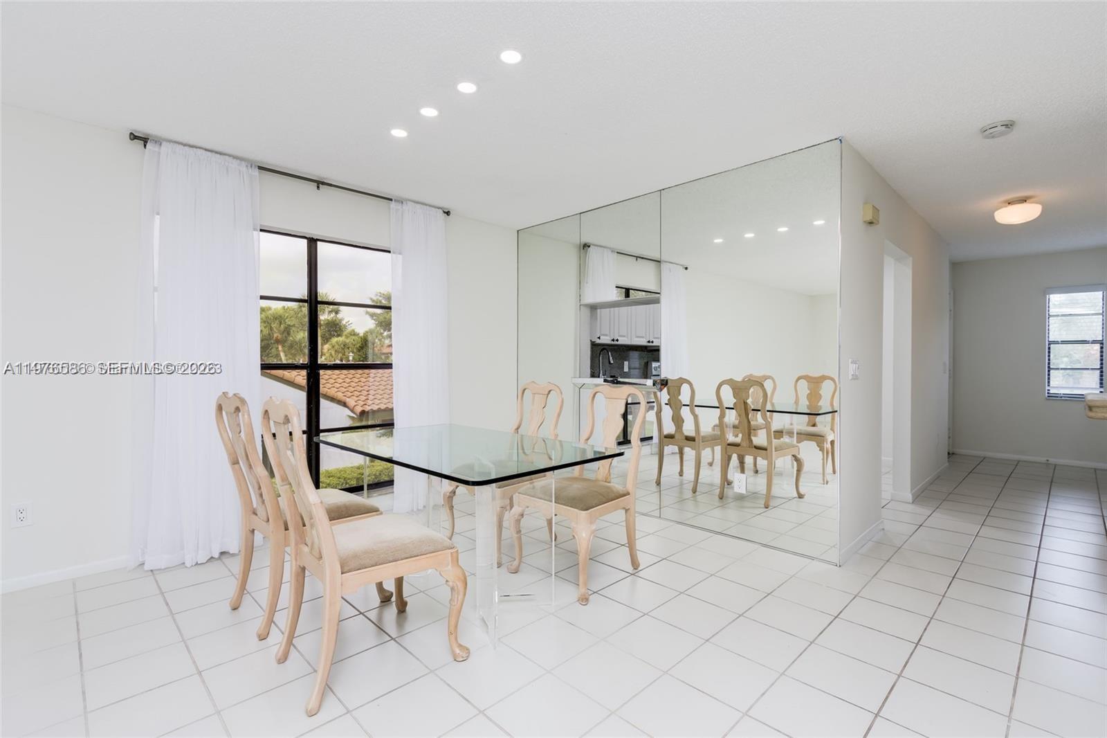 A dining room features a glass table, upholstered chairs, tiled floors, and a mirrored wall — 21529 Cypress Hammock Dr # 35J, Boca Raton FL 33428, BOCA RATON, FL