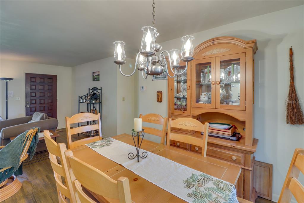 A dining room features a wooden table and hutch, a chandelier, and wood-look flooring — 20790 SW 88TH PLACE ROAD, DUNNELLON, FL