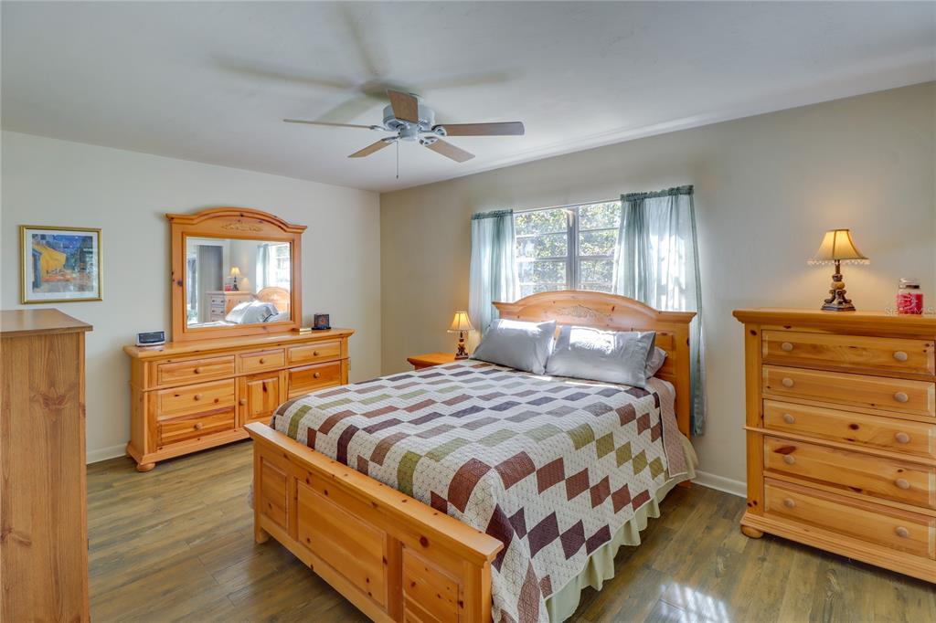A bedroom features a wooden bed frame, matching dressers, a ceiling fan, and wood-look flooring — 20790 SW 88TH PLACE ROAD, DUNNELLON, FL