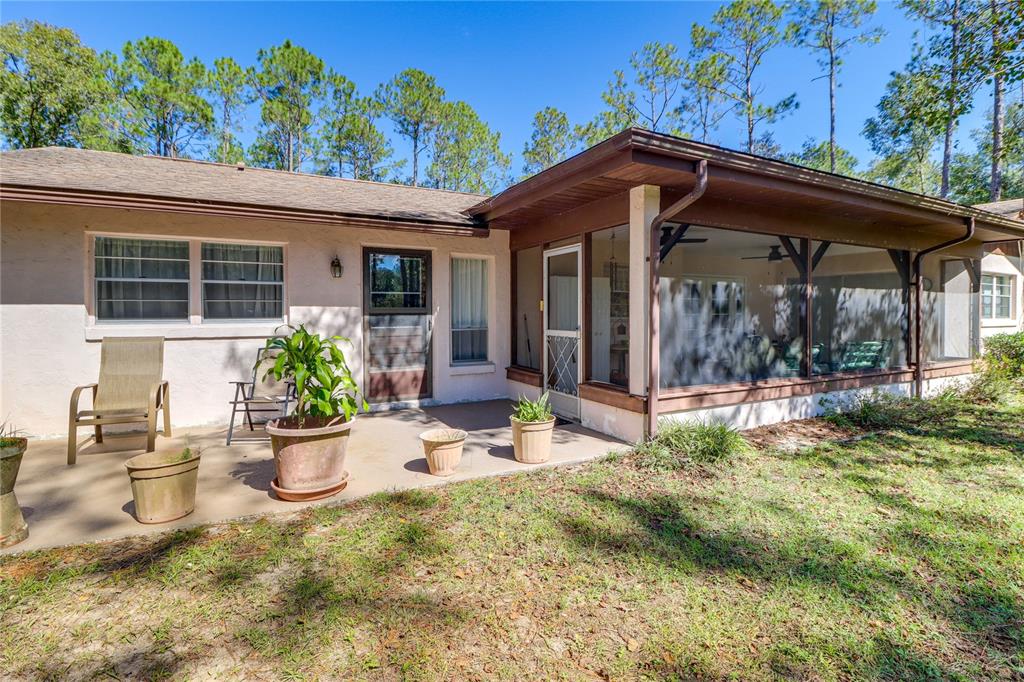 A house exterior features a concrete patio, a screened-in porch, and several potted plants — 20790 SW 88TH PLACE ROAD, DUNNELLON, FL