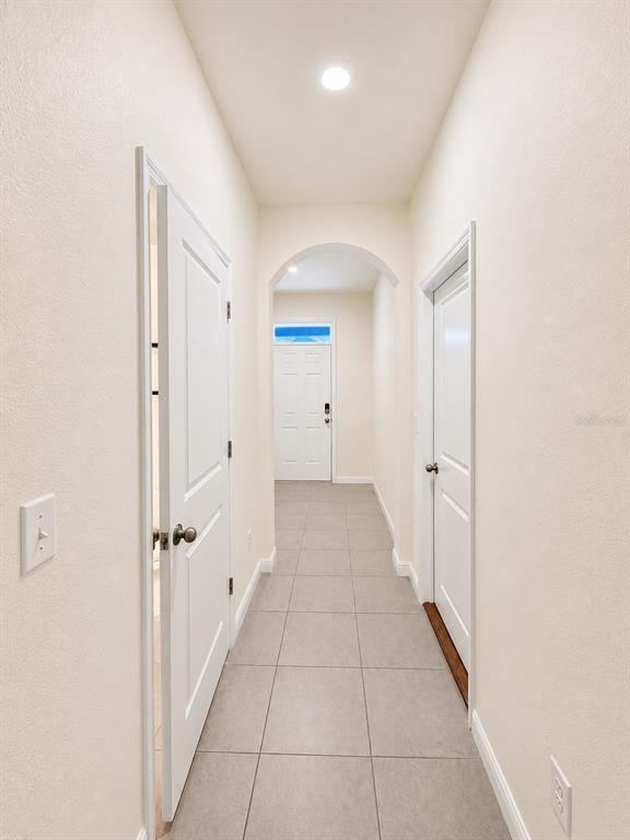 A hallway with light-colored walls, tile flooring, and two white doors leads to an entryway — 809 LUCENT SANDS COURT, BRANDON, FL