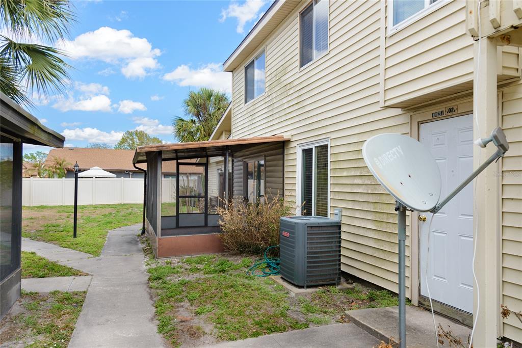 A two-story house exterior features a screened porch, a central air unit, and a satellite dish — 1023 SPRING MEADOW DRIVE UNIT 1023, KISSIMMEE, FL