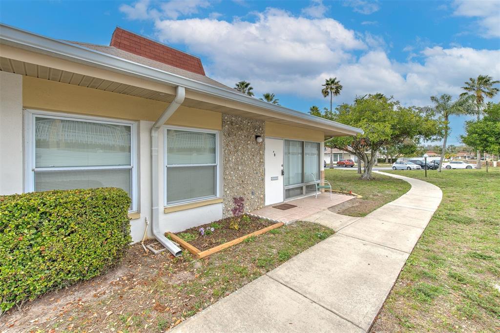 A single-story building exterior features a stone facade, a white door, and a concrete walkway — 4313 TAHITIAN GARDENS CIRCLE UNIT A, HOLIDAY, FL