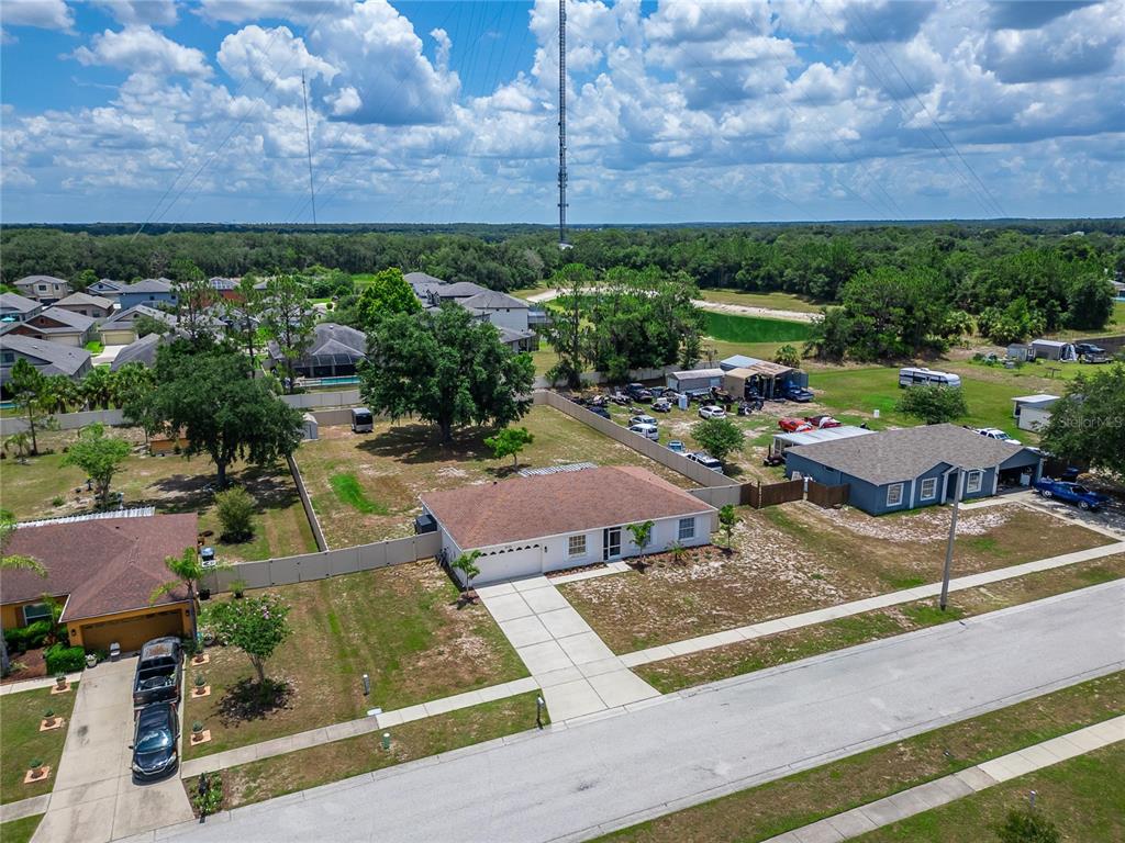 An aerial view shows a single-story house with a driveway and a fenced backyard — 12124 COLONIAL ESTATES LANE, RIVERVIEW, FL