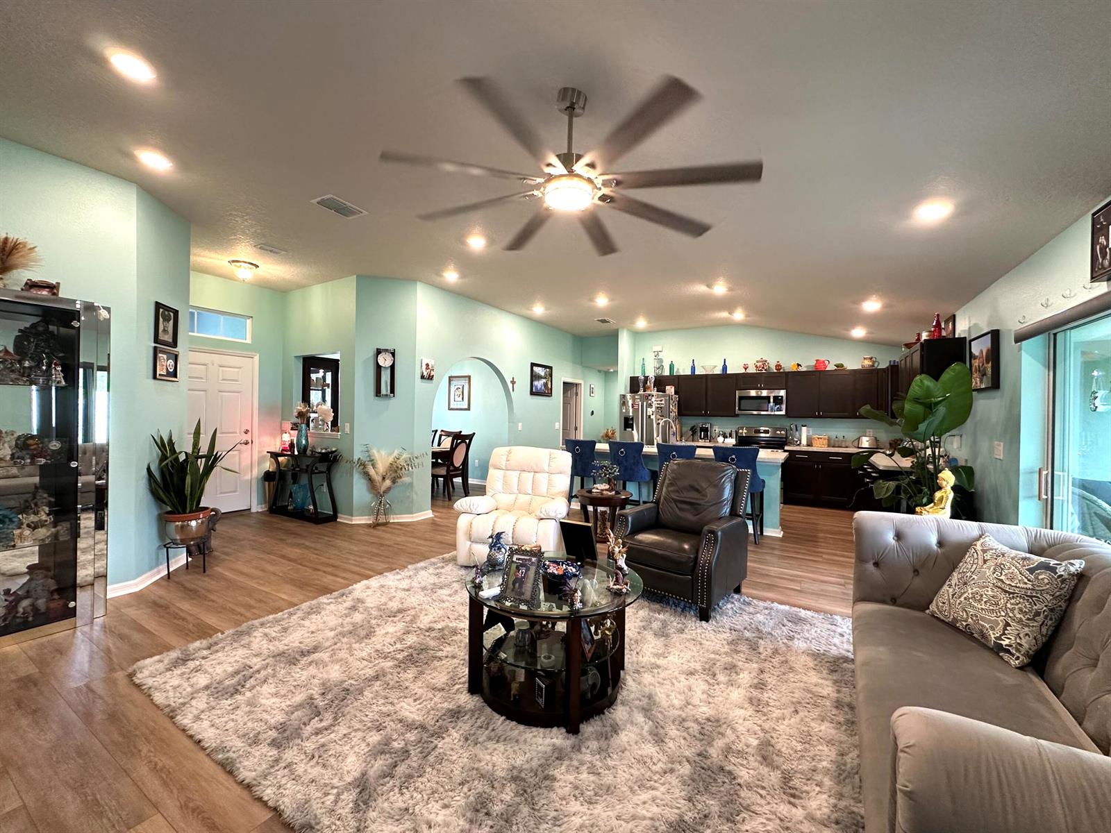 An open-concept living room features light blue walls, wood-look flooring, and a large area rug — 15329 SW 65th Ter Road, Ocala FL 34473, OCALA, FL