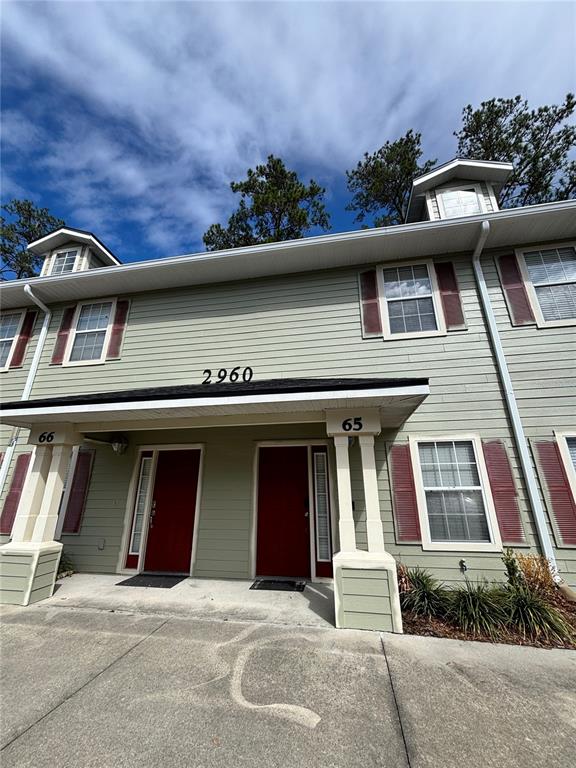 A two-story townhouse exterior features light green siding, red doors, and dark shutters — 2960 SW 35TH PLACE UNIT 65, GAINESVILLE, FL
