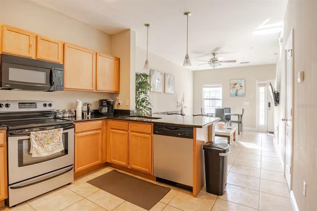 A kitchen with light wood cabinets, stainless steel appliances, and a dark granite countertop — 2960 SW 35TH PLACE UNIT 65, GAINESVILLE, FL