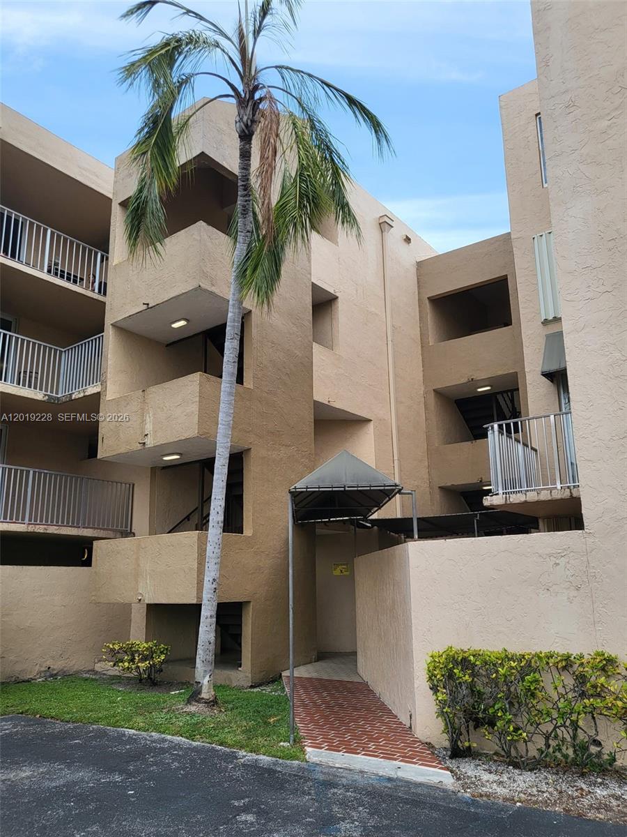 A multi-story tan stucco apartment building features exterior stairwells, balconies, and a palm tree — 10801 SW 109th Ct # D305, Miami FL 33176, MIAMI, FL