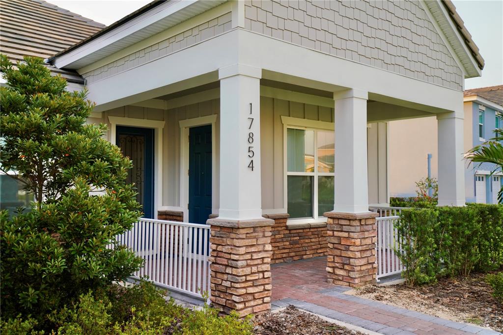 A covered front porch features white columns, stone bases, and a brick walkway — 17854 HITHER HILLS CIRCLE, WINTER GARDEN, FL