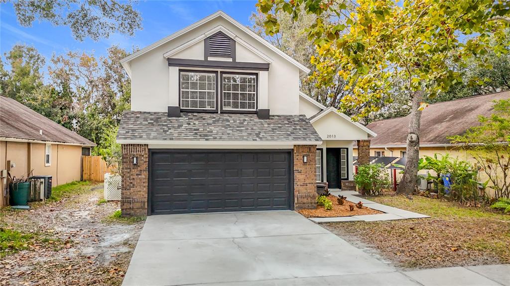 A two-story house features a dark gray garage door, brick accents, and a concrete driveway — 2013 GLEN FORGE STREET, BRANDON, FL