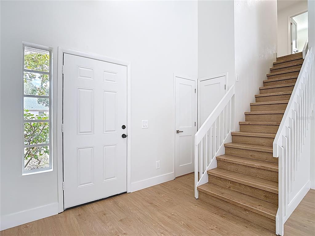 An entryway features a white front door, a tall vertical window, and wooden stairs — 2013 GLEN FORGE STREET, BRANDON, FL