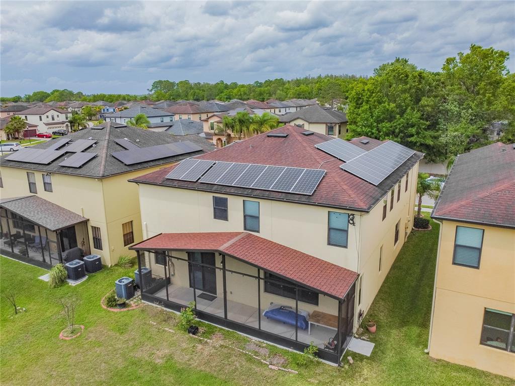 An aerial view of a two-story house with solar panels on the roof and a screened-in patio — 11027 TAHITI ISLE LANE, TAMPA, FL