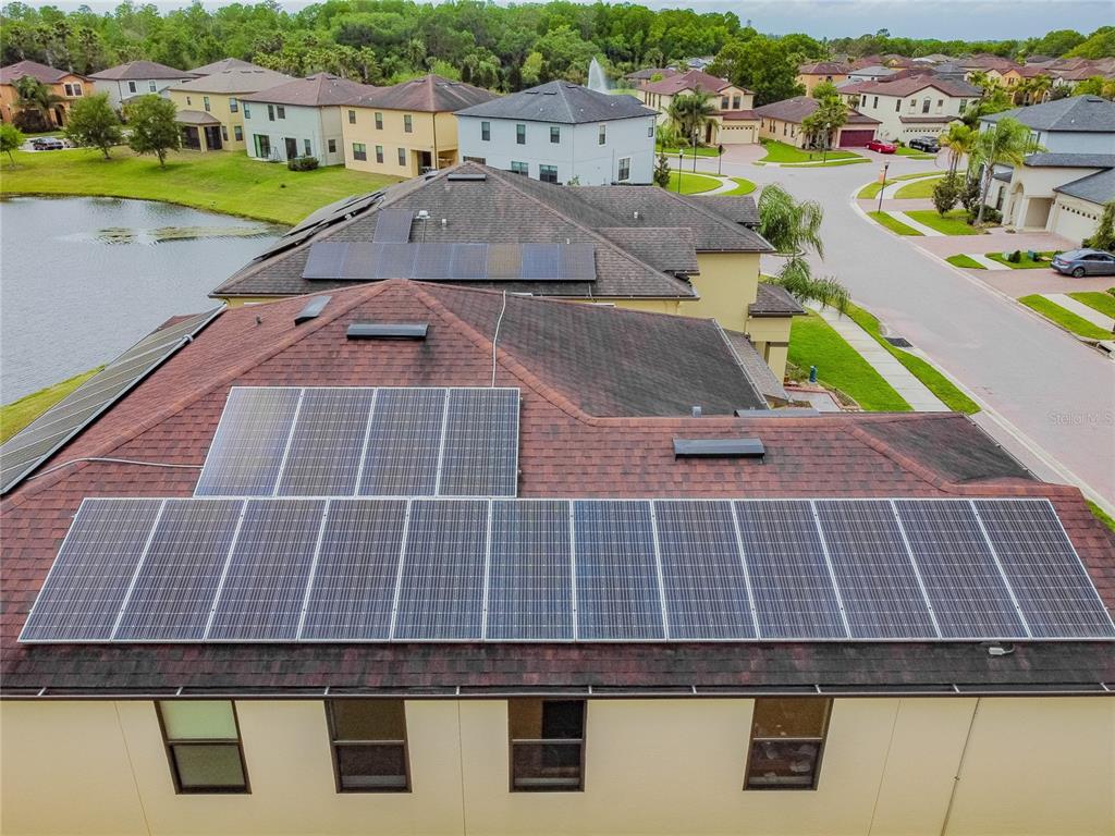 An aerial view shows a residential roof with multiple solar panel arrays installed — 11027 TAHITI ISLE LANE, TAMPA, FL