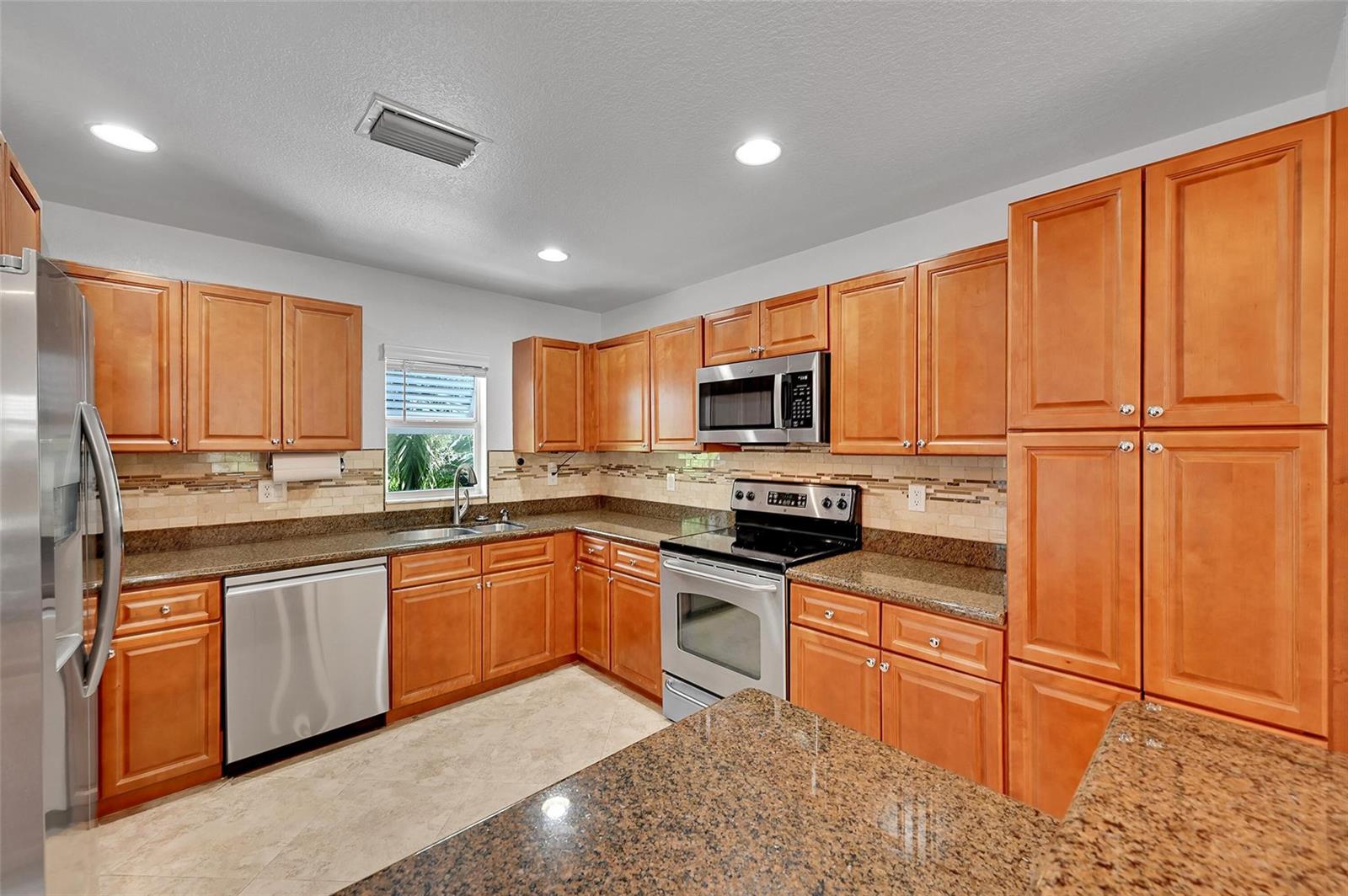 A kitchen features wood cabinets, granite countertops, stainless steel appliances, and a tile floor — 453 NE 1st Street, Pompano Beach FL 33060, POMPANO BEACH, FL