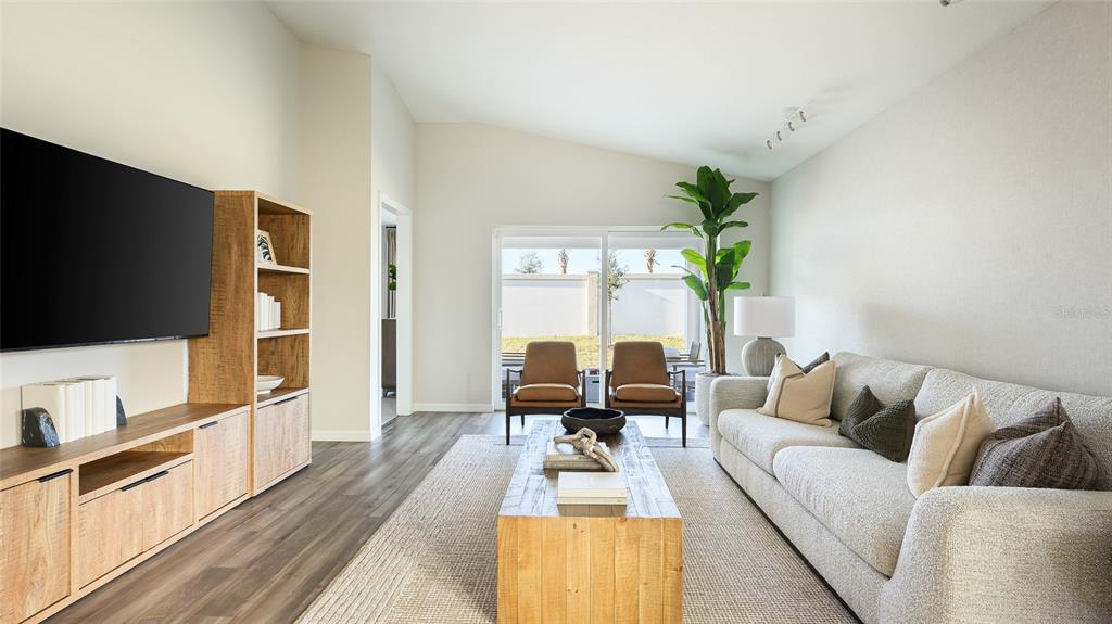 A living room features a light-colored sofa, wooden coffee table, media console, and sliding doors — 33607 NOBLE CREEK PLACE, DADE CITY, FL