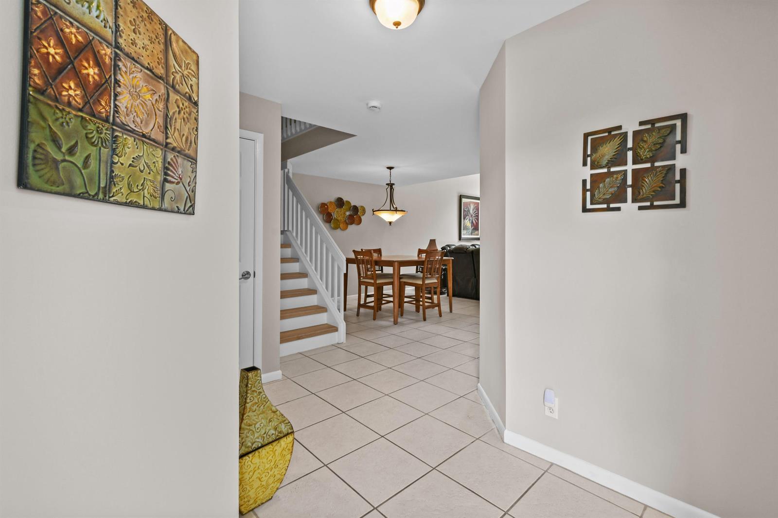 A tiled entryway leads to a dining area with a staircase and wall art — 1003 Ocean Dunes Circle, Jupiter FL 33477, JUPITER, FL