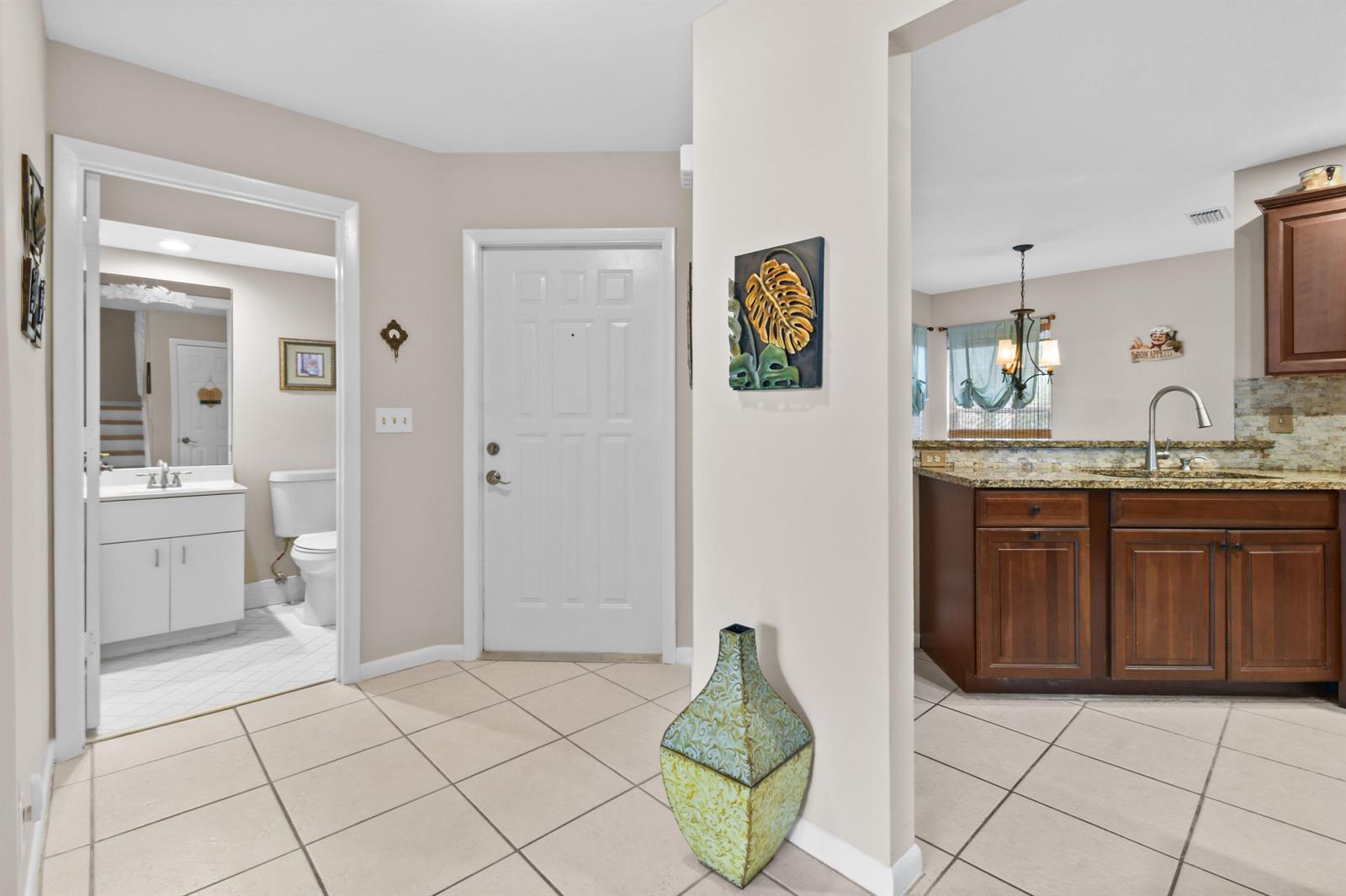 A tiled entryway leads to a bathroom, a front door, and a kitchen with cabinets — 1003 Ocean Dunes Circle, Jupiter FL 33477, JUPITER, FL