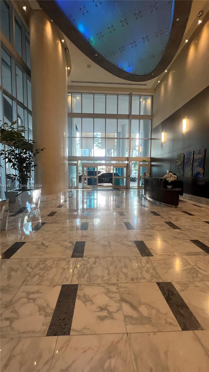 A spacious lobby features marble floors, a curved reception desk, and a high, illuminated ceiling — 185 SW 7th St # 2202, Miami FL 33130, MIAMI, FL