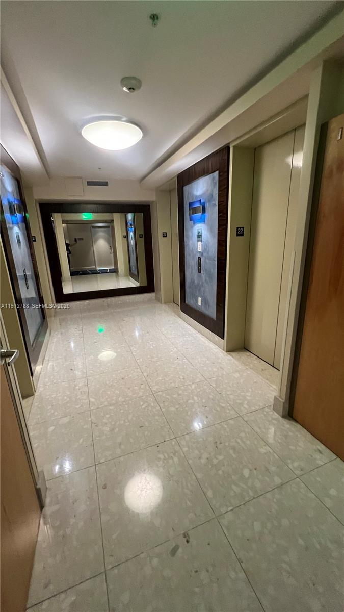 A hallway with tiled floors, elevator doors, and a large wall mirror — 185 SW 7th St # 2202, Miami FL 33130, MIAMI, FL