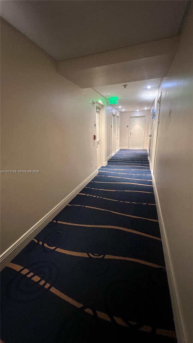 A long, narrow hotel-style hallway features blue patterned carpeting and white walls — 185 SW 7th St # 2202, Miami FL 33130, MIAMI, FL