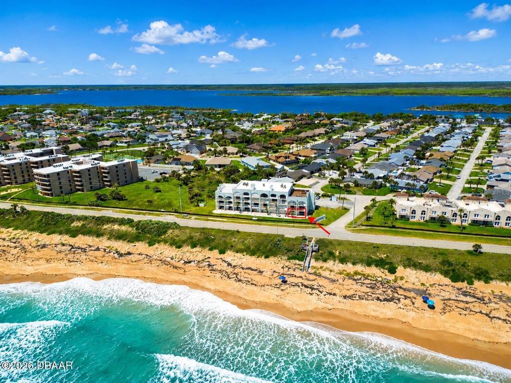 An aerial view shows a beachfront condominium building with a red-outlined ground-floor unit — 3390 OCEAN SHORE BOULEVARD UNIT 1050, ORMOND BEACH, FL